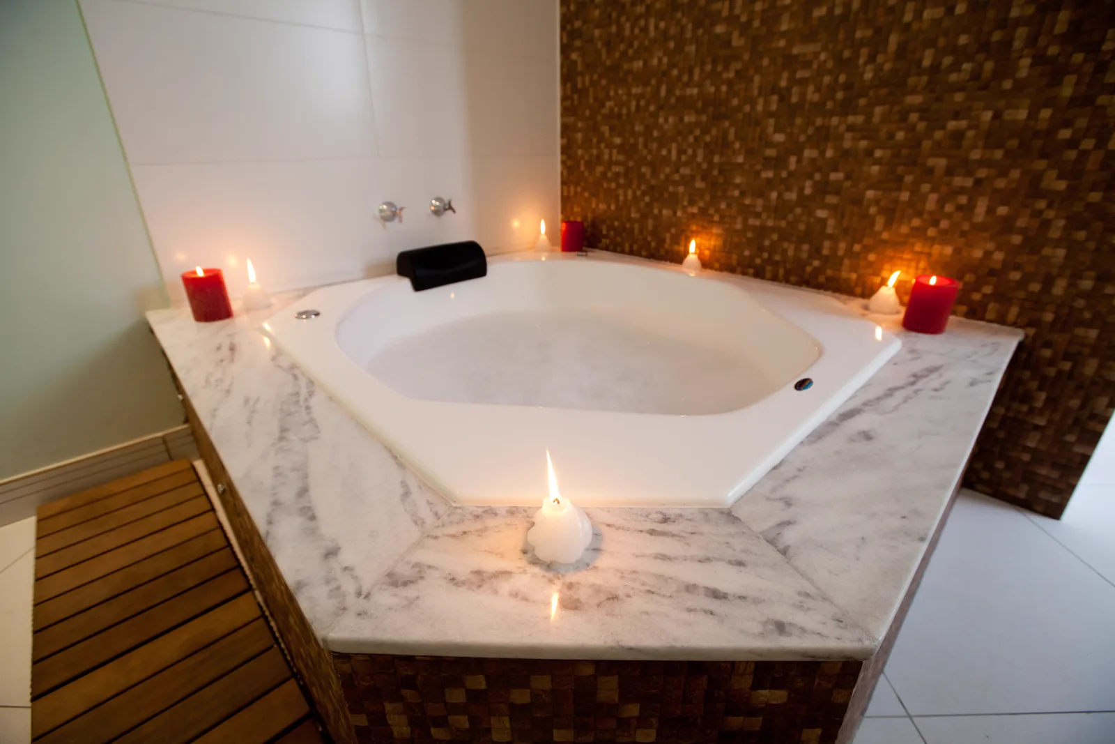 Velas acesas ao redor da banheira de hidromassagem do spa da Ergon, em Sorocaba, ambiente da candle massage