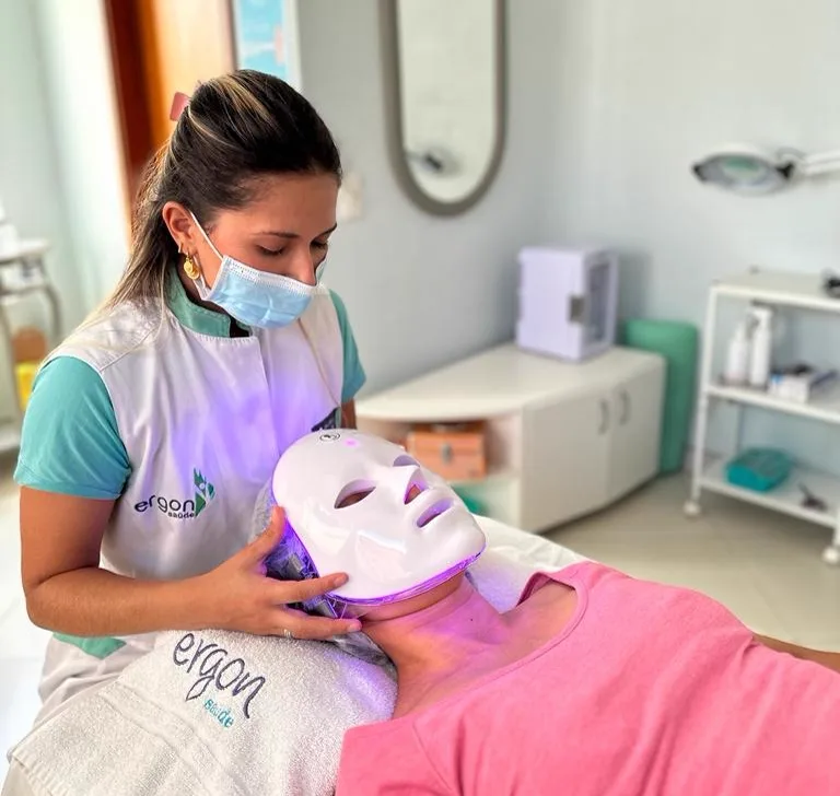 Esteticista da Ergon aplicando máscara de LED no rosto de uma cliente