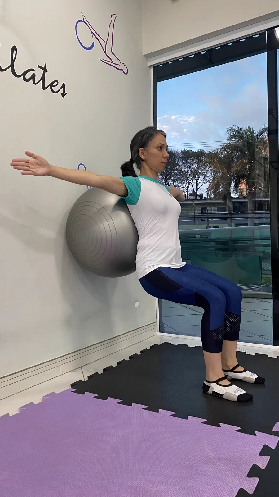 Aluna fazendo exercício de pilates com bola na parede, em Sorocaba