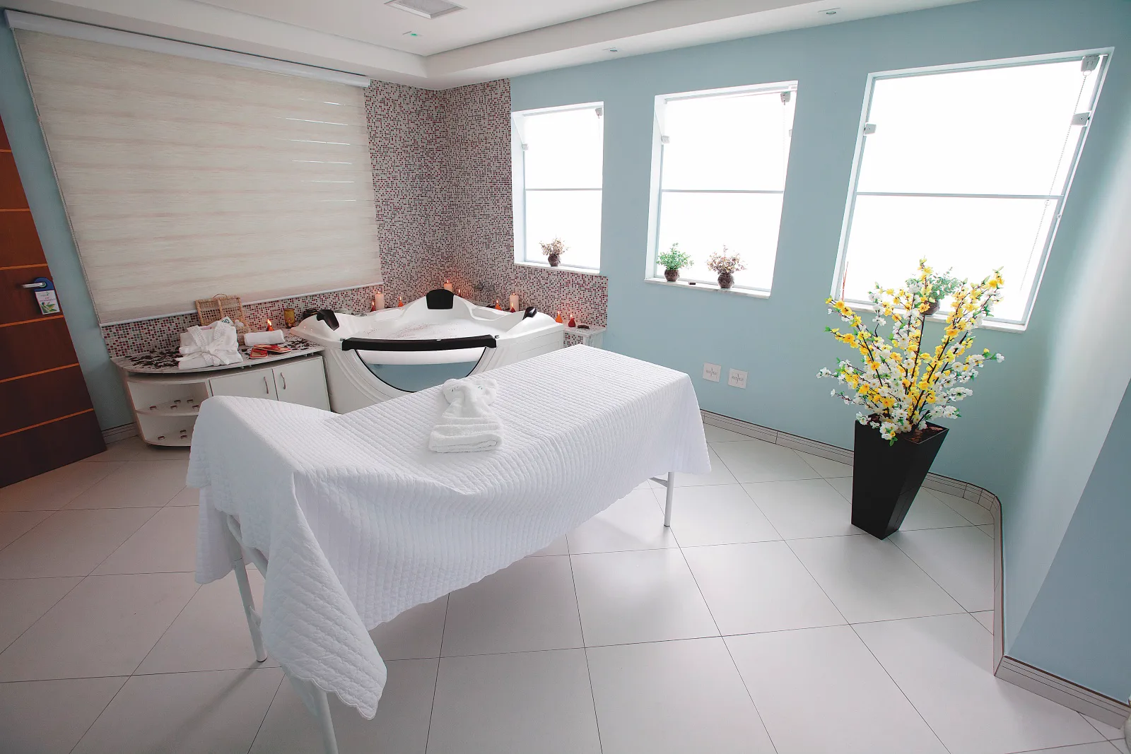Sala de spa da Ergon Saúde em Sorocaba com banheira, maca e flores, onde acontece o spa para casal