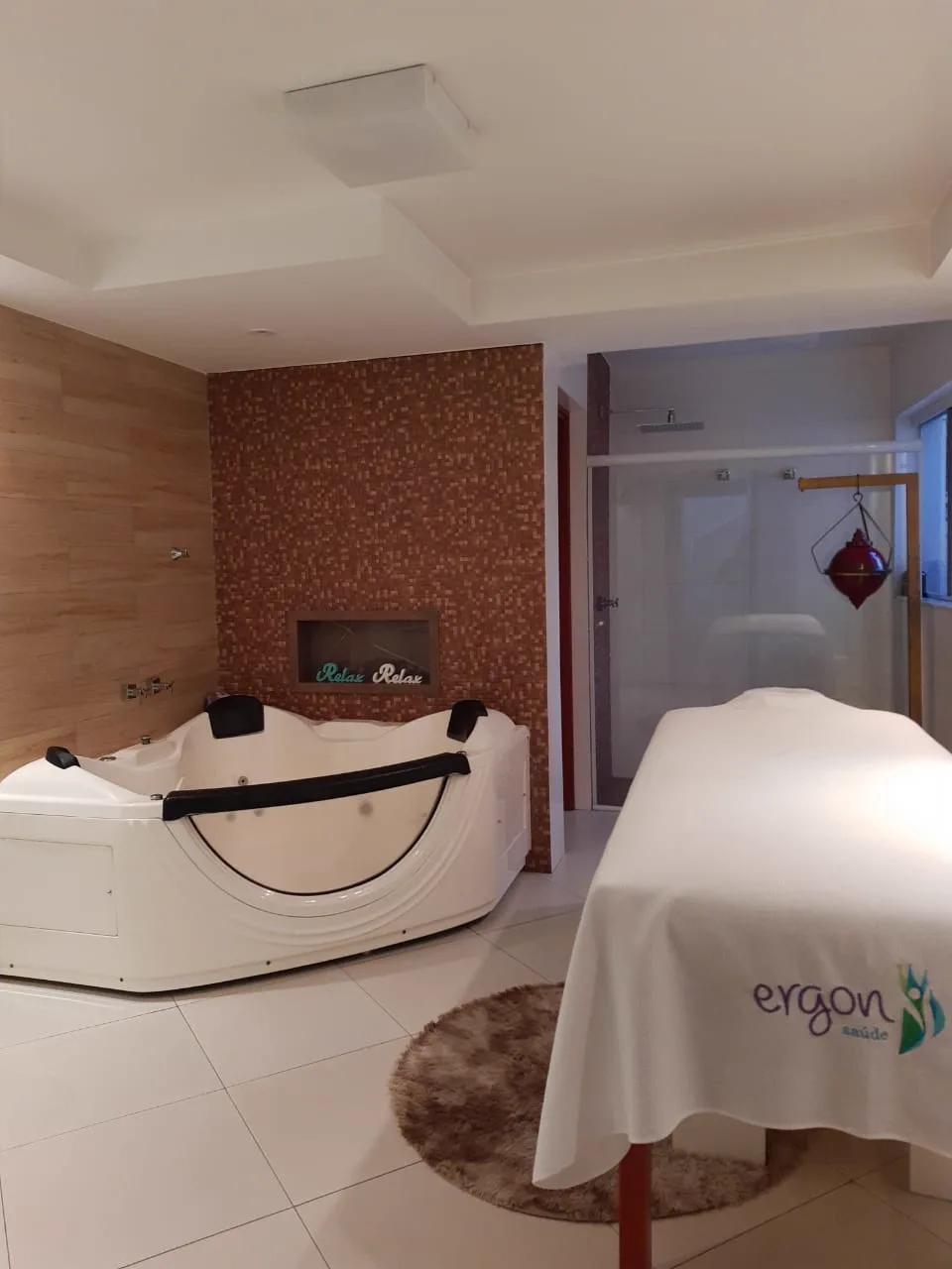 Sala de spa da Ergon com banheira de hidromassagem e maca com toalha Ergon